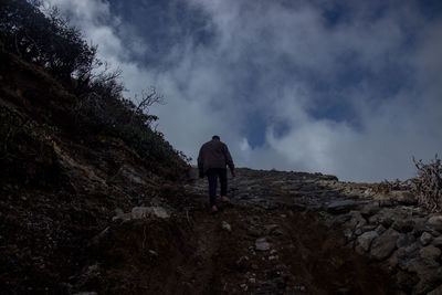 Rear view of man standing on mountain against sky