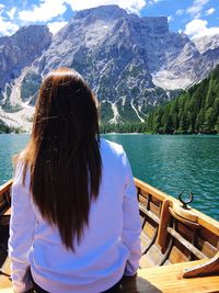 Rear view of woman on boat sailing in lake against mountains