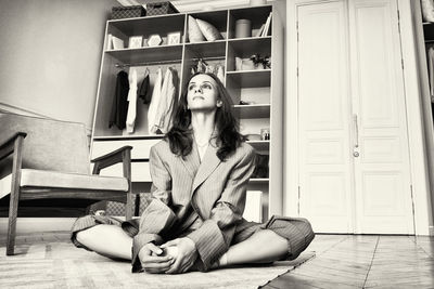 Ballerina in a gray striped suit is sitting stretching on the floor in the dressing room