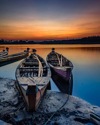 Boat moored on beach against sky during sunset