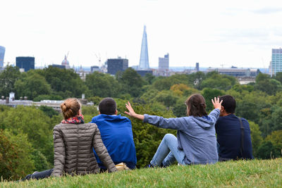 Rear view of people sitting on bench in front of building