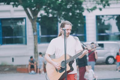 Man holding guitar while standing on street