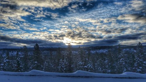 Scenic view of snow covered land against sky at sunset