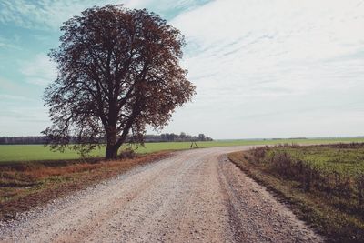 Road amidst field against sky