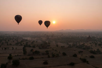 Hot air balloon flying over landscape against sky during sunset