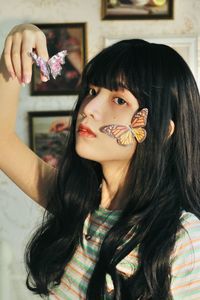 Portrait of young woman with artificial butterflies on face