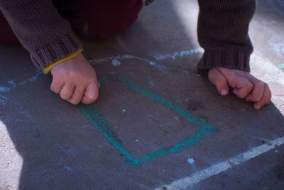 Cropped image of child writing with chalk on surface