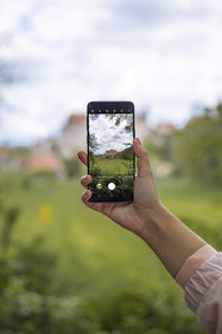 Person holding smart phone against sky