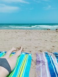 Low section of young woman relaxing at beach