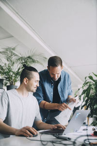 Creative businessmen discussing over document at desk in office