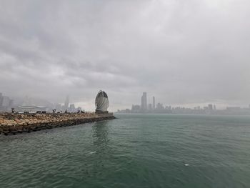 View of buildings in sea against cloudy sky
