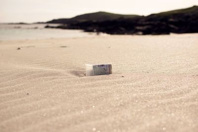 Plastic cup on beach against sky