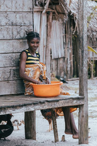 Portrait of smiling young woman sitting on wood