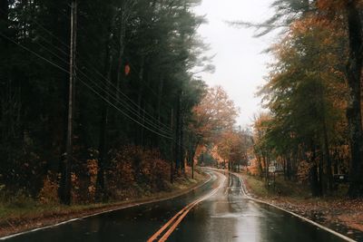 Road amidst trees in forest against sky