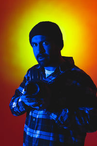 Young man standing against yellow background