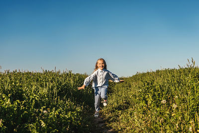 Girl running on land against clear sky