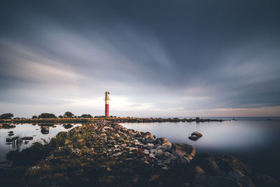 Lighthouse by sea against sky, long exposure. 