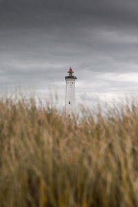 Lighthouse behind grass-covered dunes