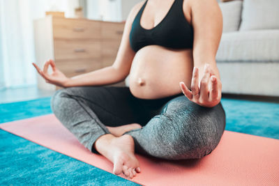 Low section of woman doing yoga at home