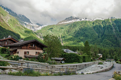 Houses by trees and buildings against sky