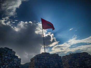 Low angle view of flag against buildings against sky