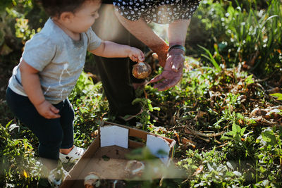 Baby boy with grandmother holding vegetable at farm