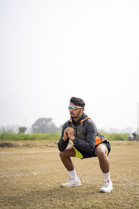 Young indian sports man doing squats in the field. sports and healthy lifestyle concept.