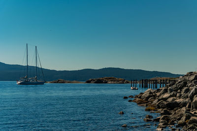 A rocky pier at the sunshine coast with a sailing boat