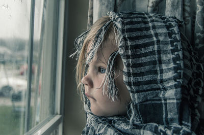 Close-up of cute girl looking through window