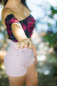 Midsection of teenage girl with hands raised standing against lake