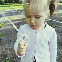 Girl holding dandelion at park
