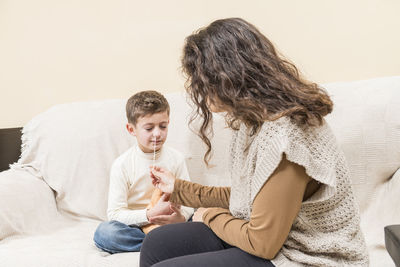 Side view of mother and daughter sitting on sofa at home