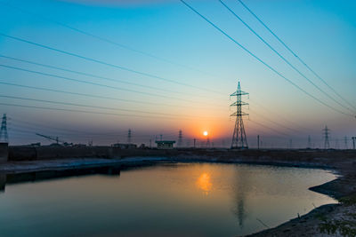 Reflection of electricity pylon against sky during sunset