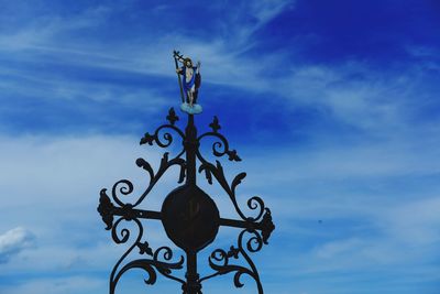 Low angle view of cross sculpture against sky