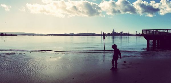 Boy standing in sea against sky