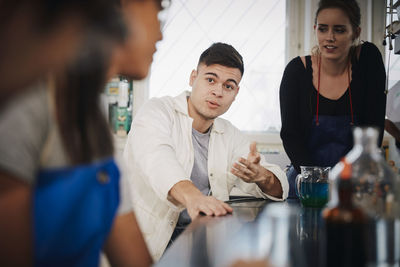 Young multi-ethnic chemistry students discussing in university laboratory