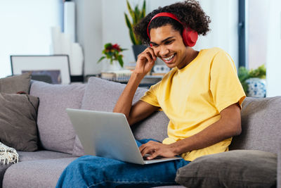 Young woman using laptop while sitting on sofa at home