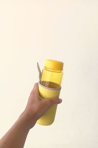 Close-up of hand holding drink against white background