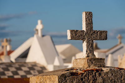 Close-up of cross in cemetery against sky