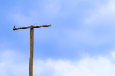 Low angle view of cross on pole against sky