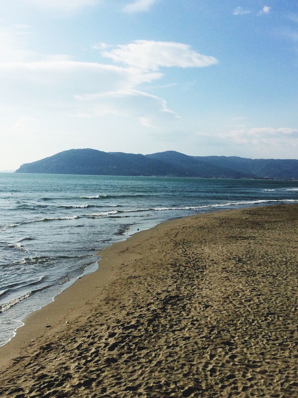 beach, water, sand, sea, sky, tranquil scene, shore, tranquility, scenics, beauty in nature, nature, mountain, coastline, idyllic, cloud - sky, cloud, day, remote, outdoors, calm