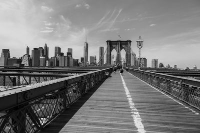 Brooklyn bridge by modern buildings against sky