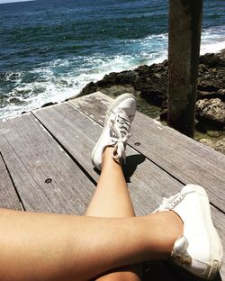 Low section of woman on pier against sea