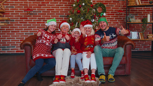 Cheerful family sitting on sofa against christmas tree at home