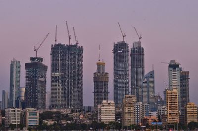 Skyscrapers in city against sky during sunset