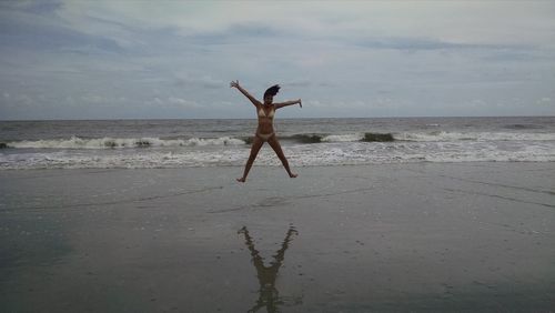 Man jumping on beach against sky