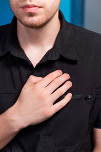 A young man stands and makes himself a lymphatic massage with his hand in the chest area, close-up