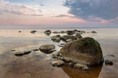 Rocks on beach against sky during sunset