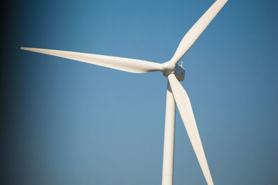 Low angle view of wind turbine against clear blue sky