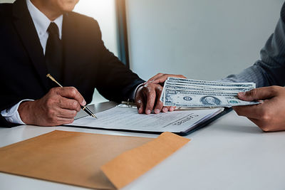 Midsection of man holding paper in pen on table